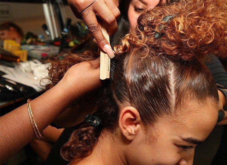 Stylist securing the second bubble ponytail with elastic.