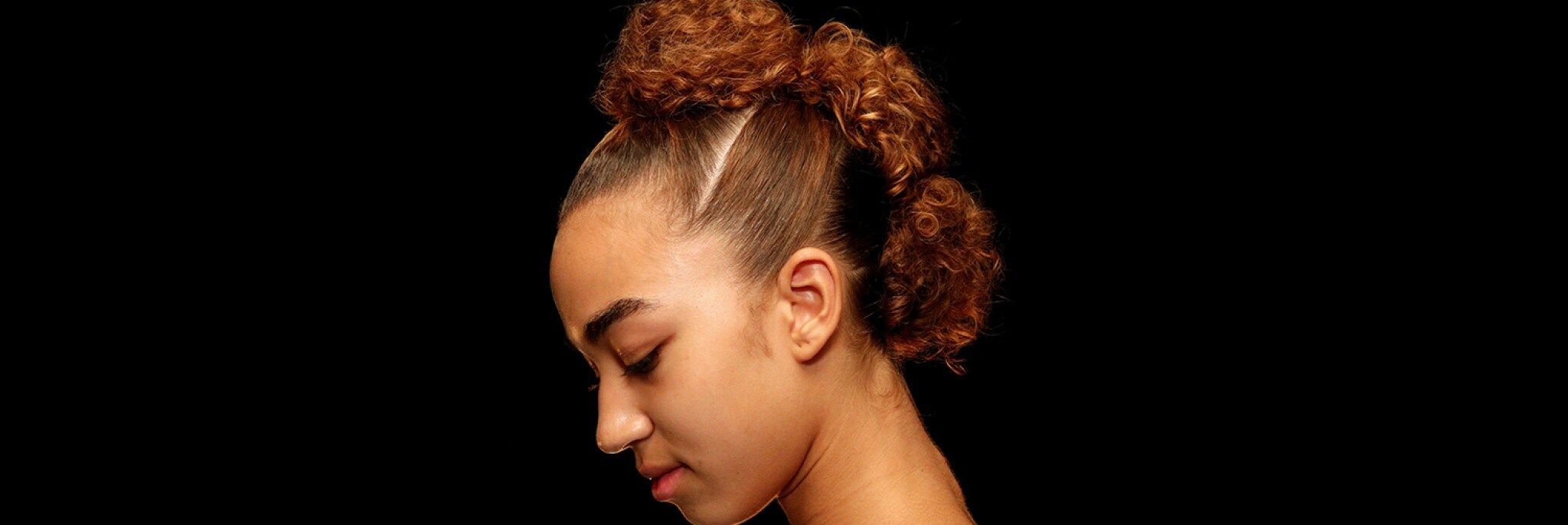 Beautiful woman with bublle braids against a black background.