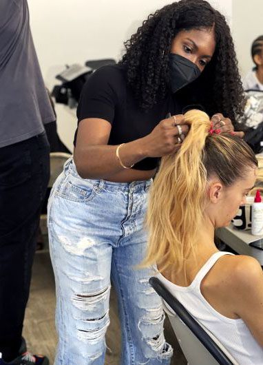 Stylist gathering model's hair into a ponytail.