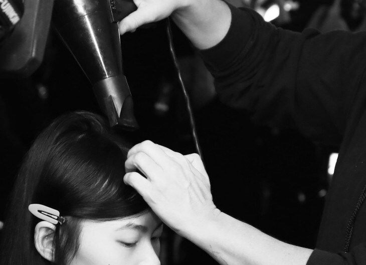 Stylists blowdrying model's hair