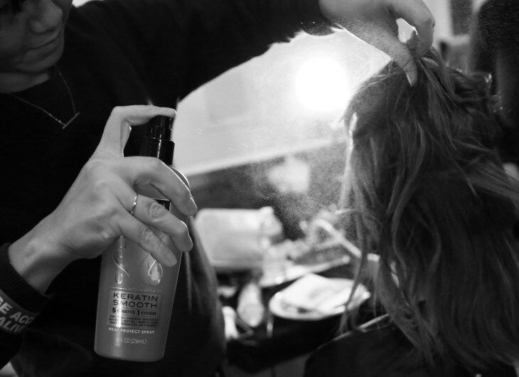 Stylist using TRESemmé Keratin Smooth Heat Protection Spray on model's hair