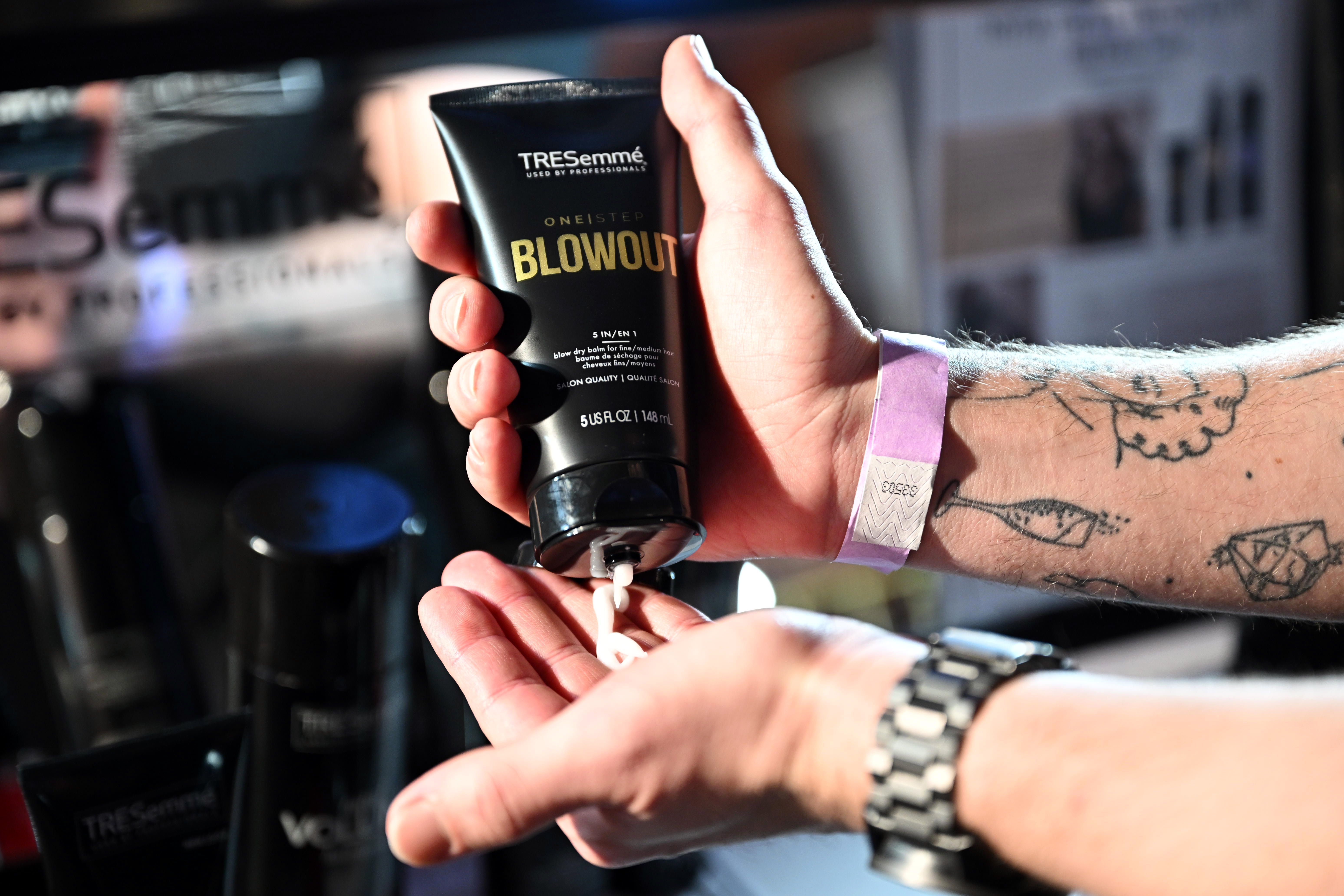 Stylist pouring TRESemmé Blowout balm from bottle into their hand