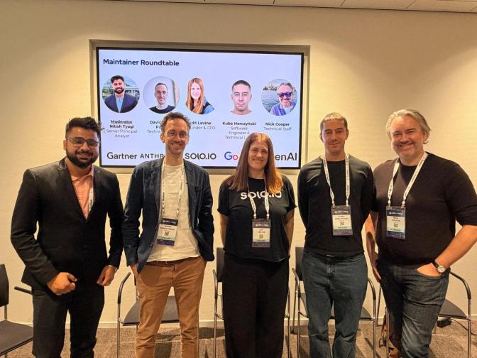 Five panelists standing in front of a screen displaying "Maintainer Roundtable" with logos from Gartner, Anthropic, Solo.io, Google, and OpenAI.
