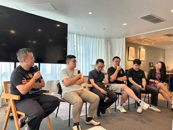 Panel of six people sitting in chairs during a discussion or Q&A session in a modern office space.