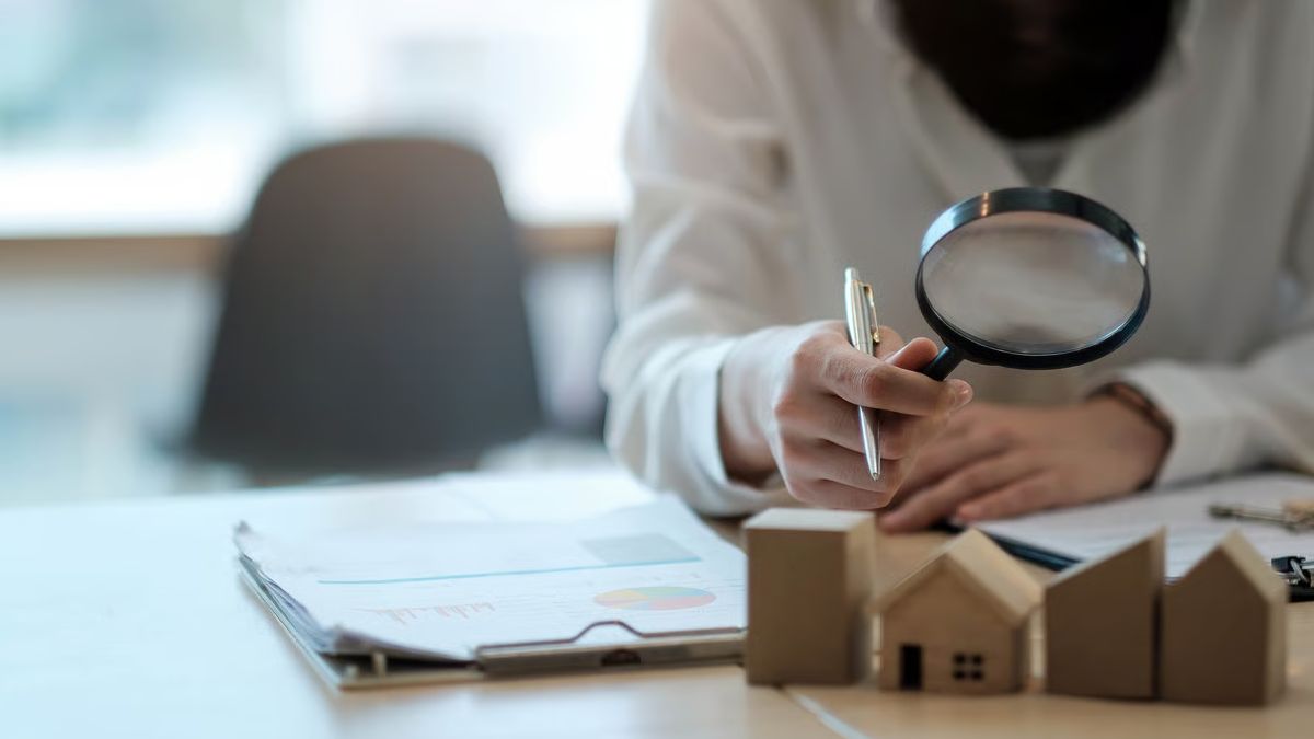 Persona con lupa examinando documentos, en referencia a la transparencia y verificación de una subasta de propiedades en Macal