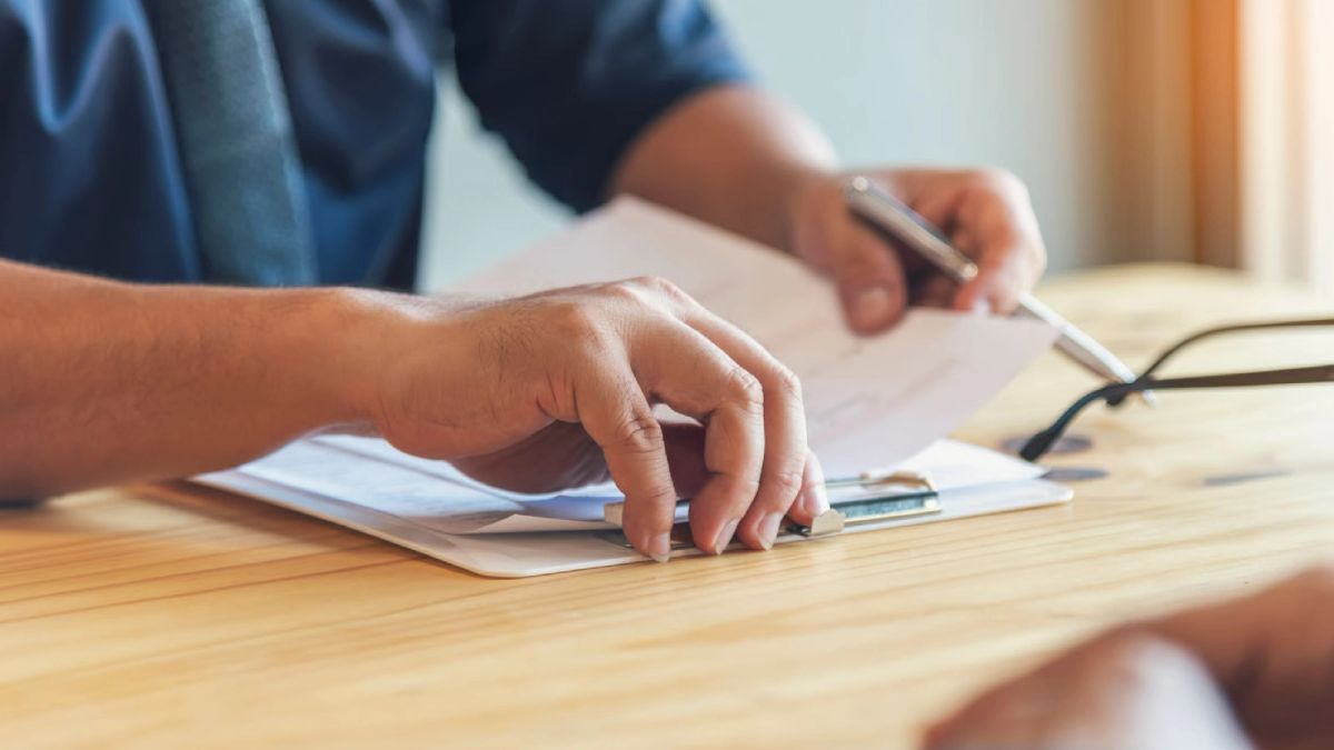 Persona firmando documentos para vender su propiedad rápido por remate o subasta con Macal