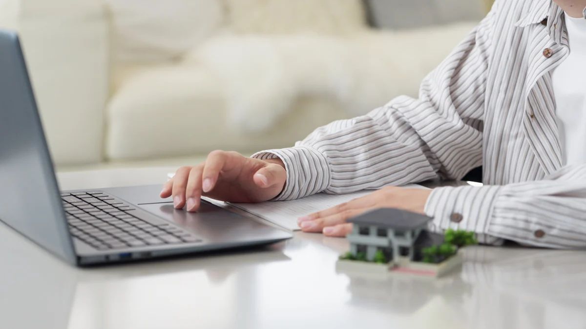 Persona revisando propiedades por internet en su computador, comparando portales inmobiliarios vs subastas