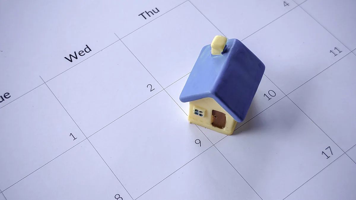 Casa en miniatura sobre un calendario, que representa la fecha definida para vender una propiedad por subasta