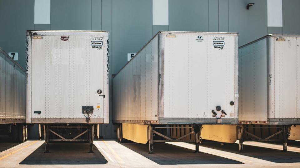 Białe naczepy chłodnicze stojące pod rampami magazynowymi - transport w temperaturze kontrolowanej. Białe naczepy chłodnicze stojące pod rampami magazynowymi - transport w temperaturze kontrolowanej.