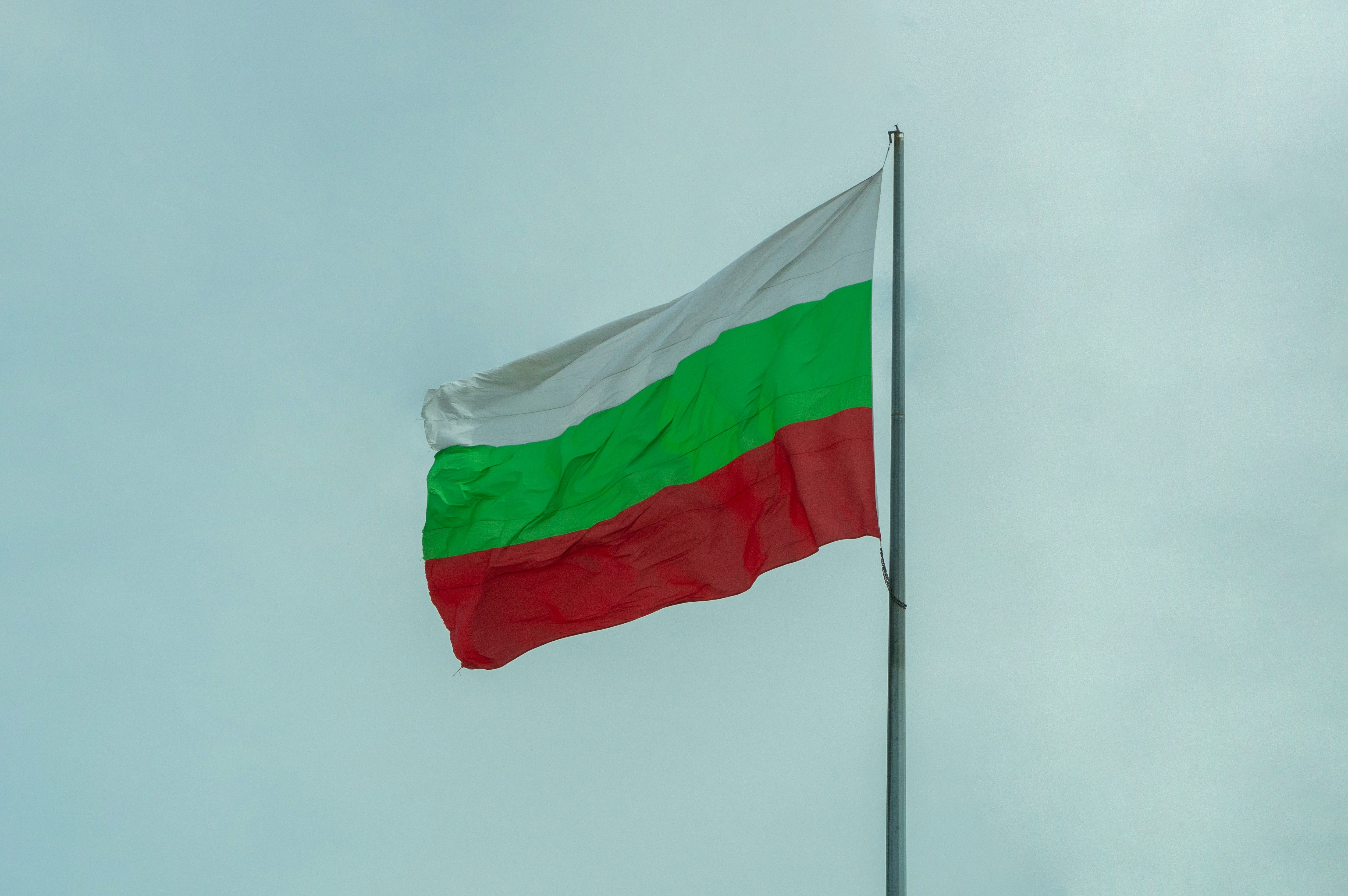 Flaga Węgier na maszcie powiewa na wietrze na tle bezchmurnego nieba.