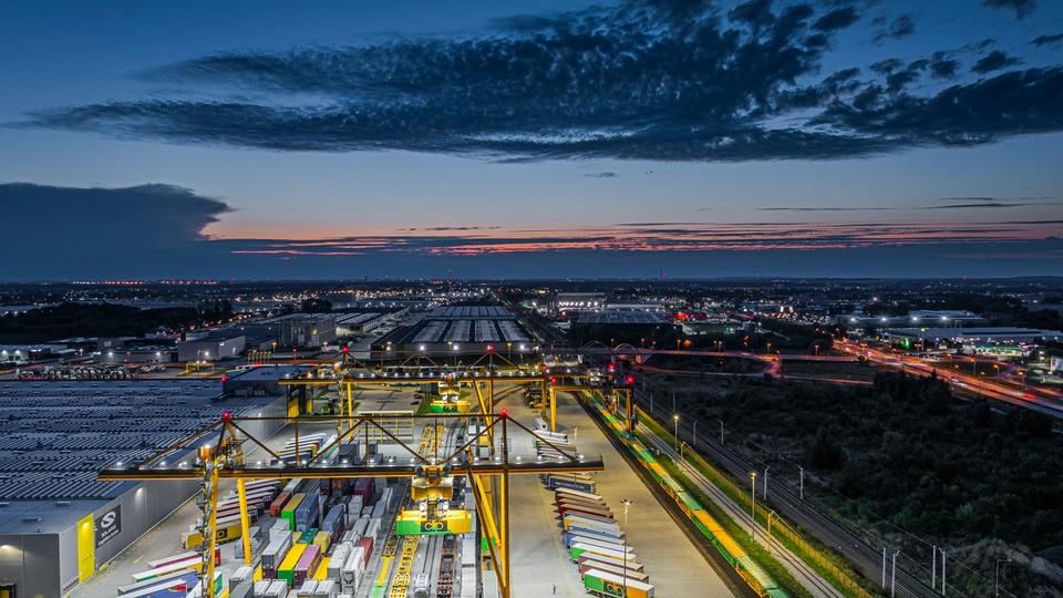 Terminal przeładunkowy i centrum logistyczne TSL z dźwigami bramowymi do cross-dockingu i przeładunku intermodalnego o zmierzchu. Terminal przeładunkowy i centrum logistyczne TSL z dźwigami bramowymi do cross-dockingu i przeładunku intermodalnego o zmierzchu.