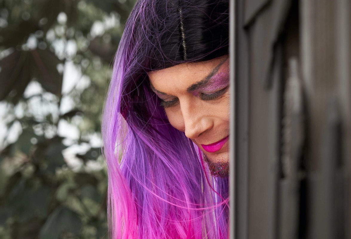 Drag queen with purple hair looking down