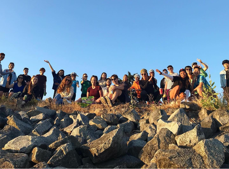 Group of approximately 20 Chill Rides members standing at the top of a ledge of rocks smilling. 