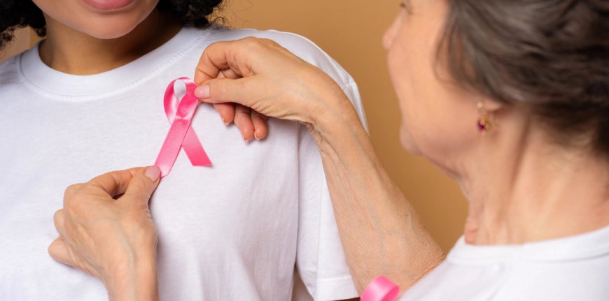 someone putting a pink ribbon on another persons white shirt
