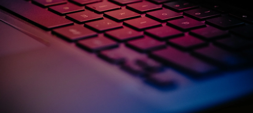 Up close laptop keyboard, purple light
