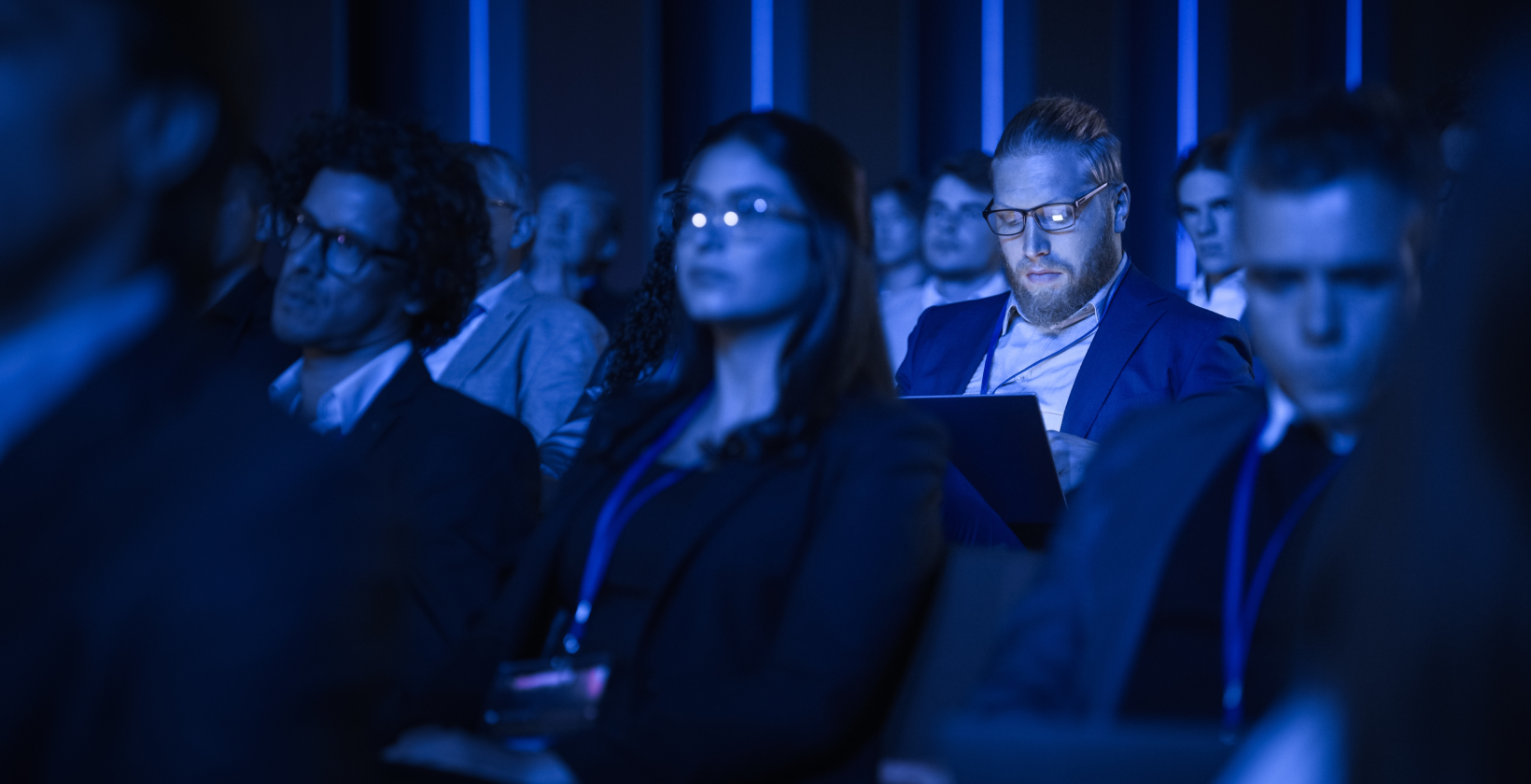 Man lit by laptop in dark conference room