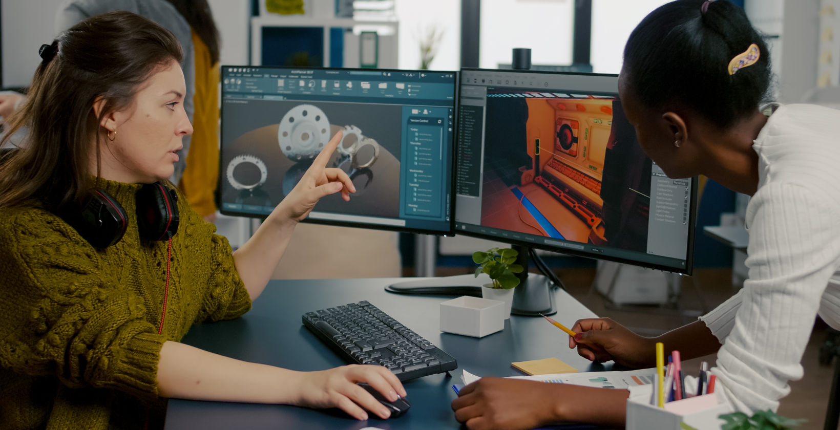 two women looking at two desktop screens
