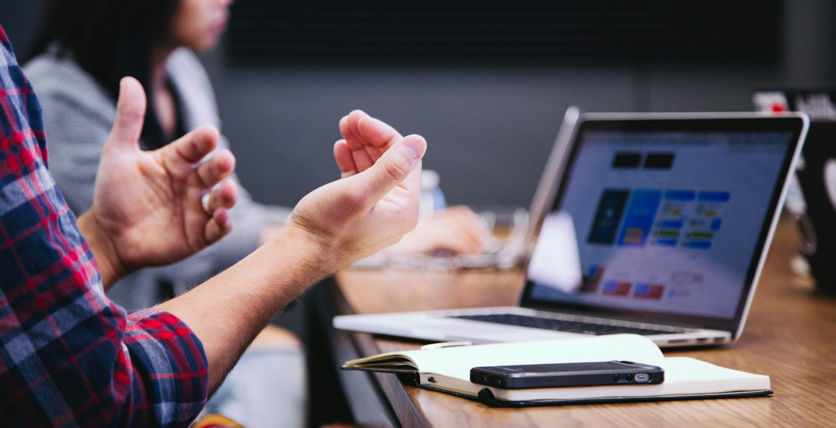 Two hands next to laptop and notebook