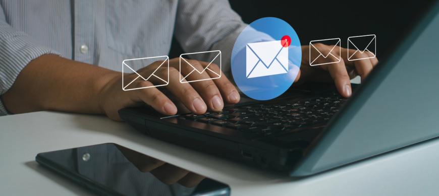 Email icons hovering above person typing on laptop