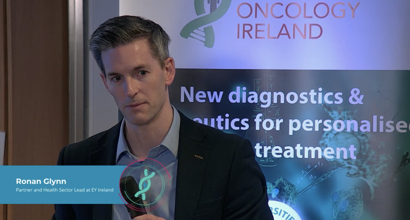 Ronan Glynn presenting at healthcare event, showing idents