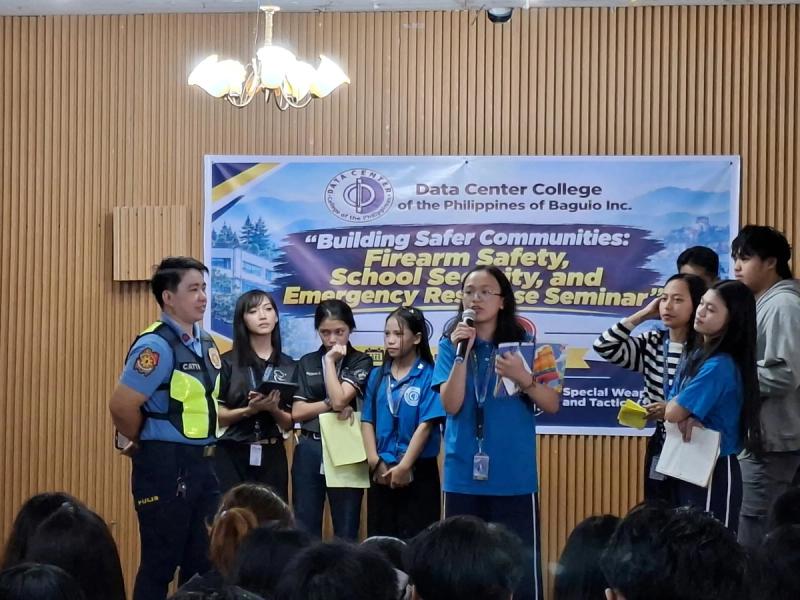 Police officer addressing students and officials during the seminar, with the Building Safer Communities banner in the background