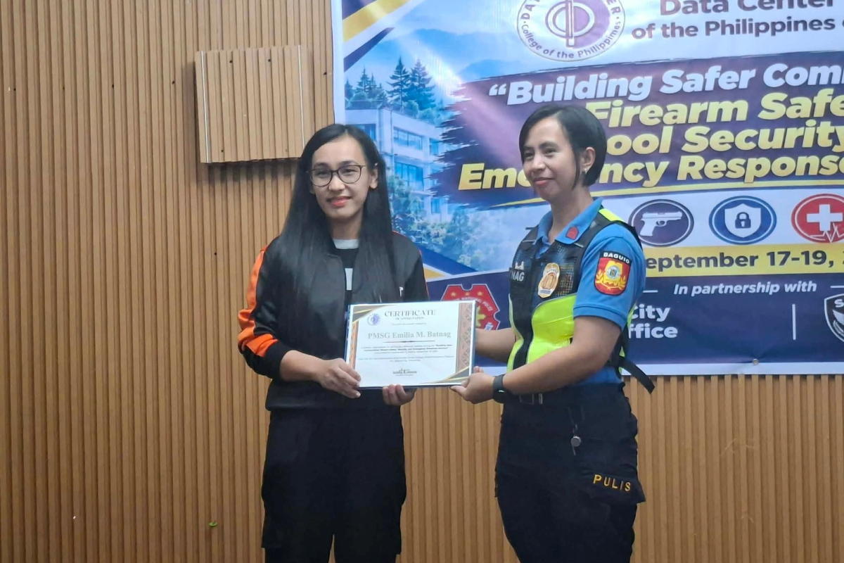 DCCP representative and a Baguio City police officer holding a certificate of recognition in front of the seminar banner