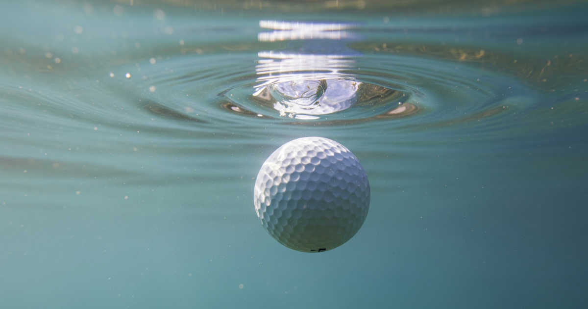 Biodegradable golf ball entering water and beginning the dissolution process