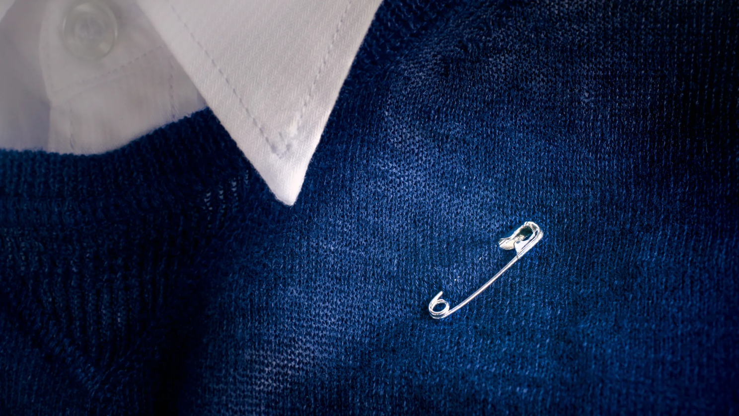 Blue jumper with a safety pin on it