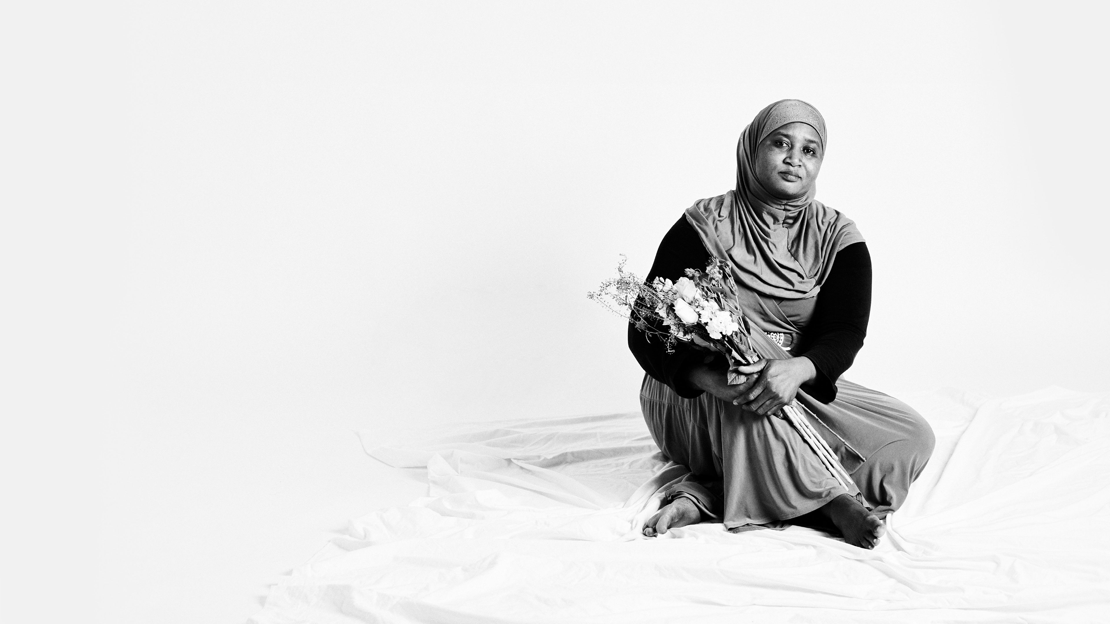 Photo of an FGM survivor looking empowered holding some flowers