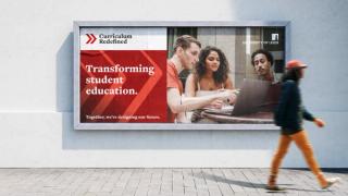 Person walking in front of billboard advert for Curriculum Redefined