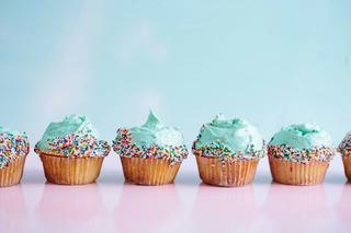 5 blue cupcakes with sprinkles are lined up one next to the other