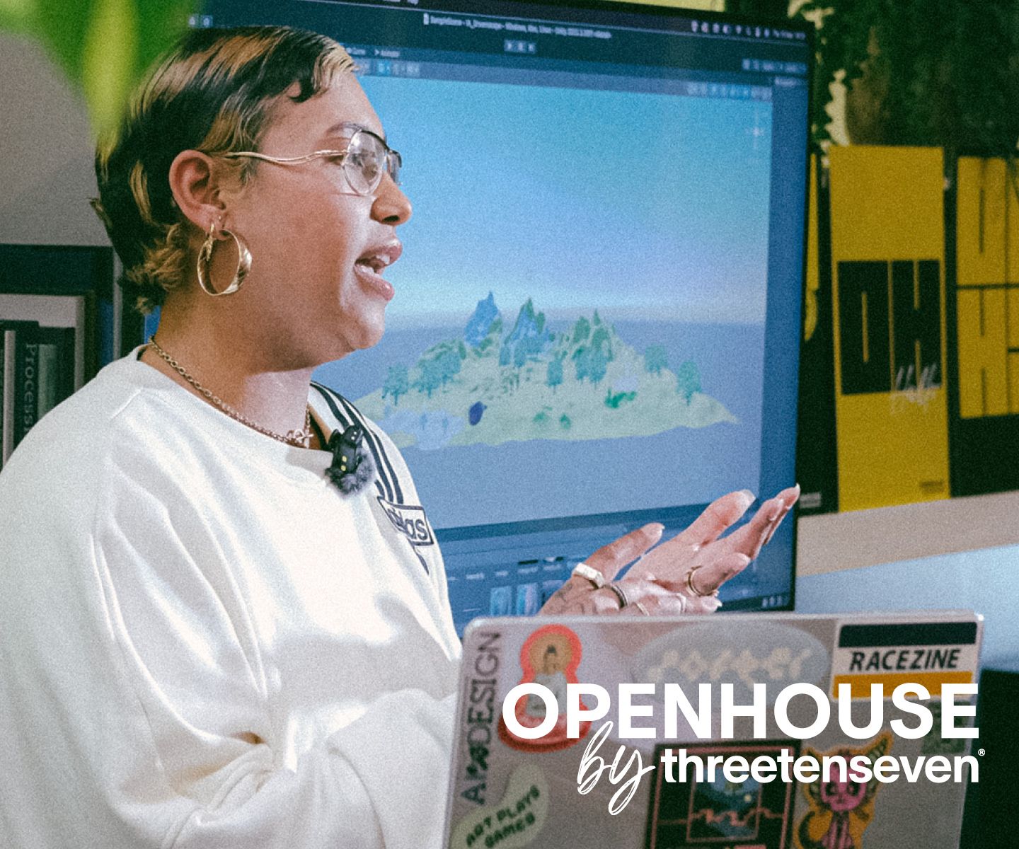 Openhouse by ThreeTenSeven: woman is talking animatedly to an audience, off camera, in a creative studio and with a laptop covered in stickers just in shot.