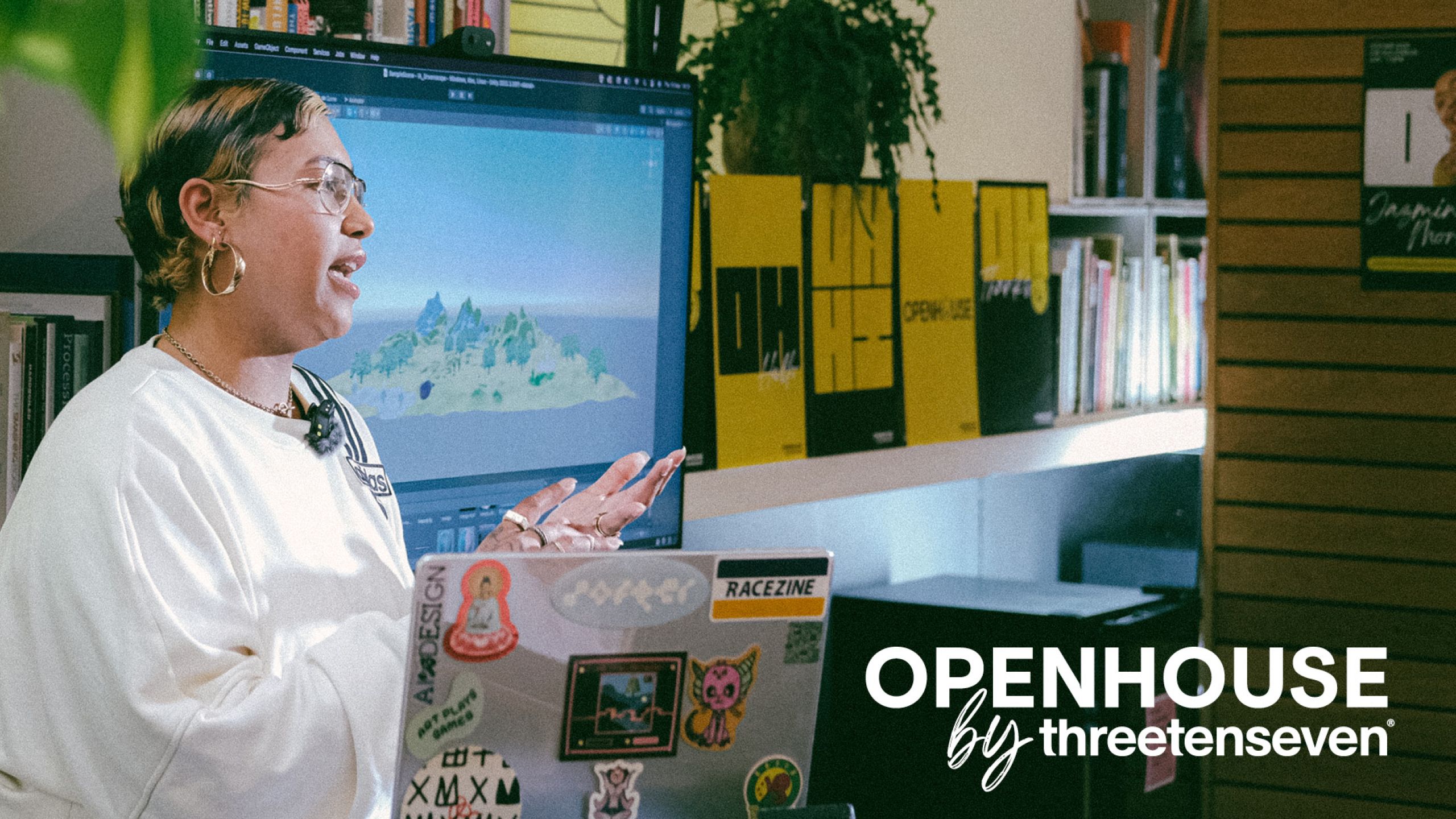 Openhouse by ThreeTenSeven: woman is talking animatedly to an audience, off camera, in a creative studio and with a laptop covered in stickers just in shot.