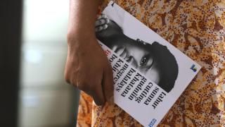 FGM survivor holding Talking Is Healing booklet