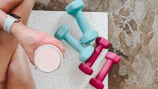 Woman with a health drink and a set of colourful weights