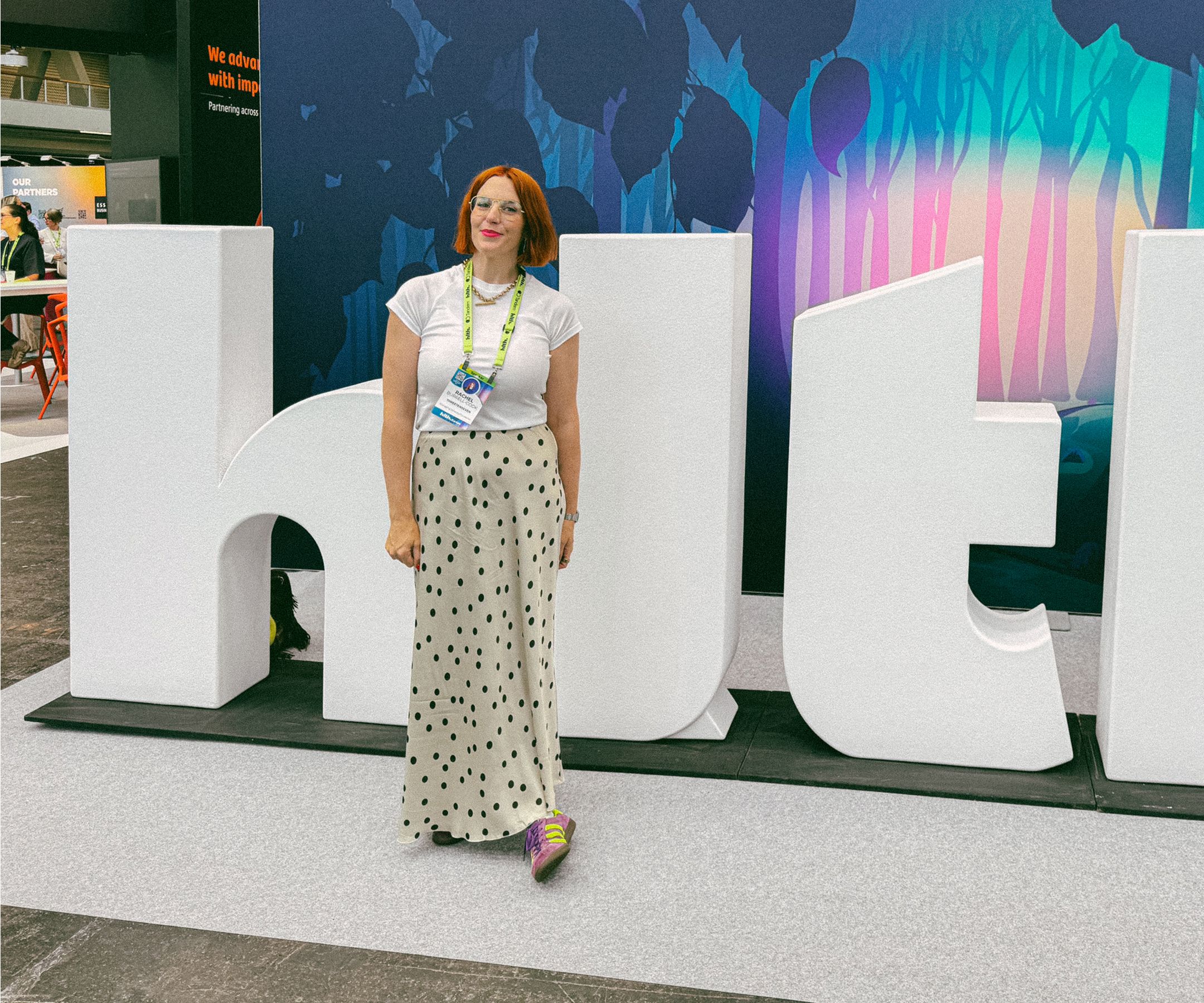 Rachel standing in front of a giant HLTH sign at the HLTH Europe conference.