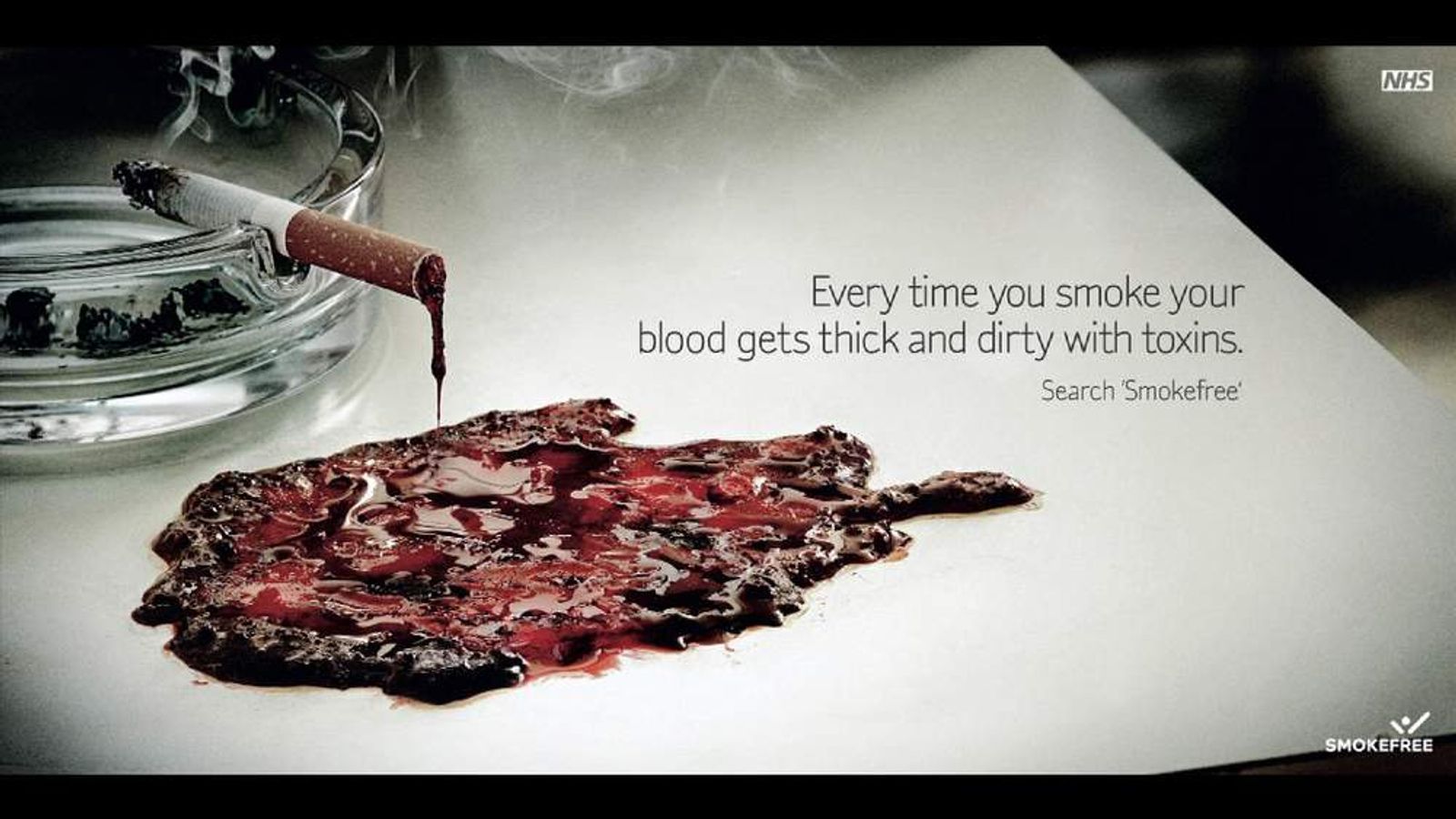 Awful grim advert, all grey and smoky, featuring a picture of a cigarette on an ashtray dripping tar and blood. Text reads: Every time you smoke your blood gets thick and dirty with toxins. Search Smokefree. NHS Logo.