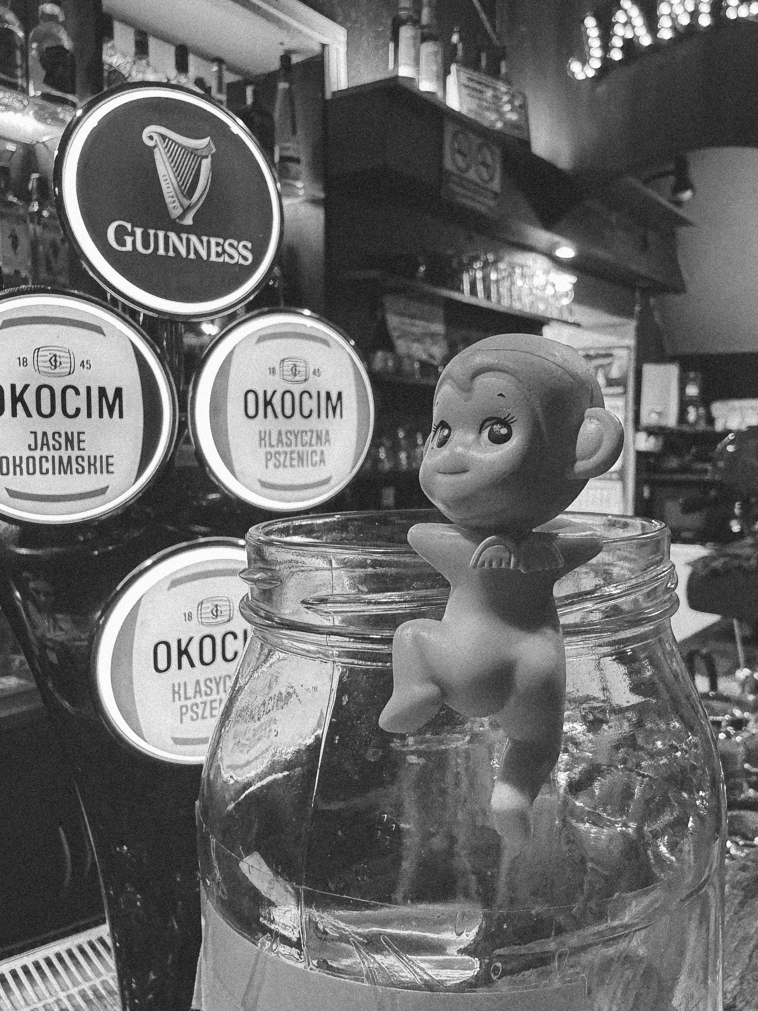 Naked monkey toy climbing a glass jar in a bar