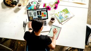 Person working at a desk using an iPad and laptop