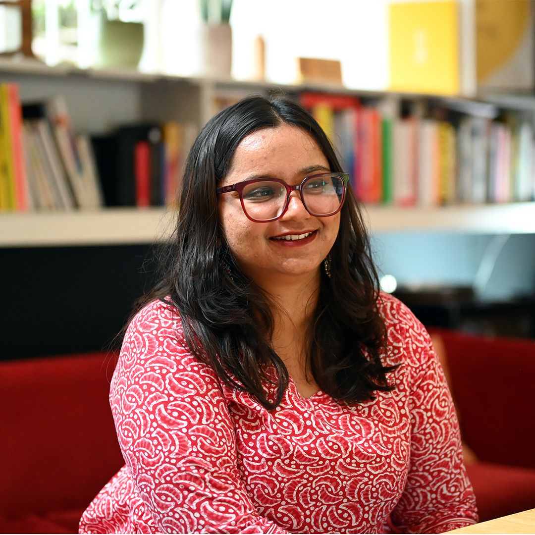 Aashini, our intern sits in front of a book shelf