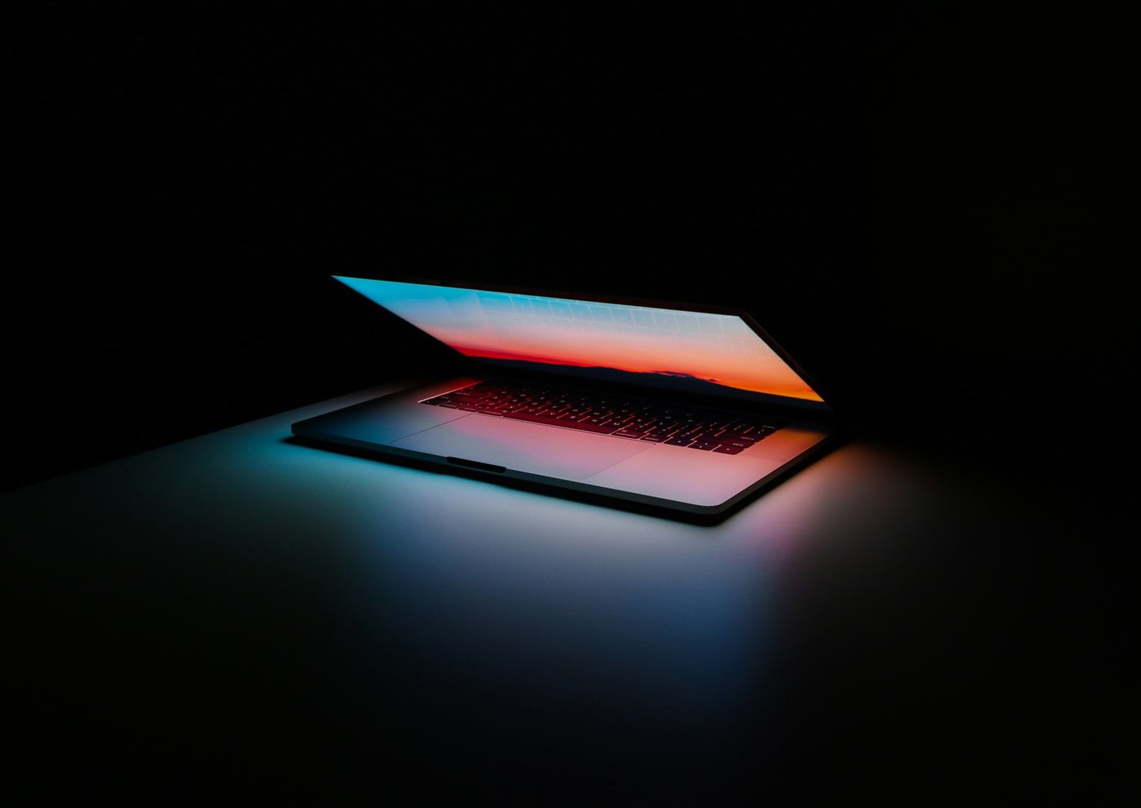 Laptop glowing onto a black desk