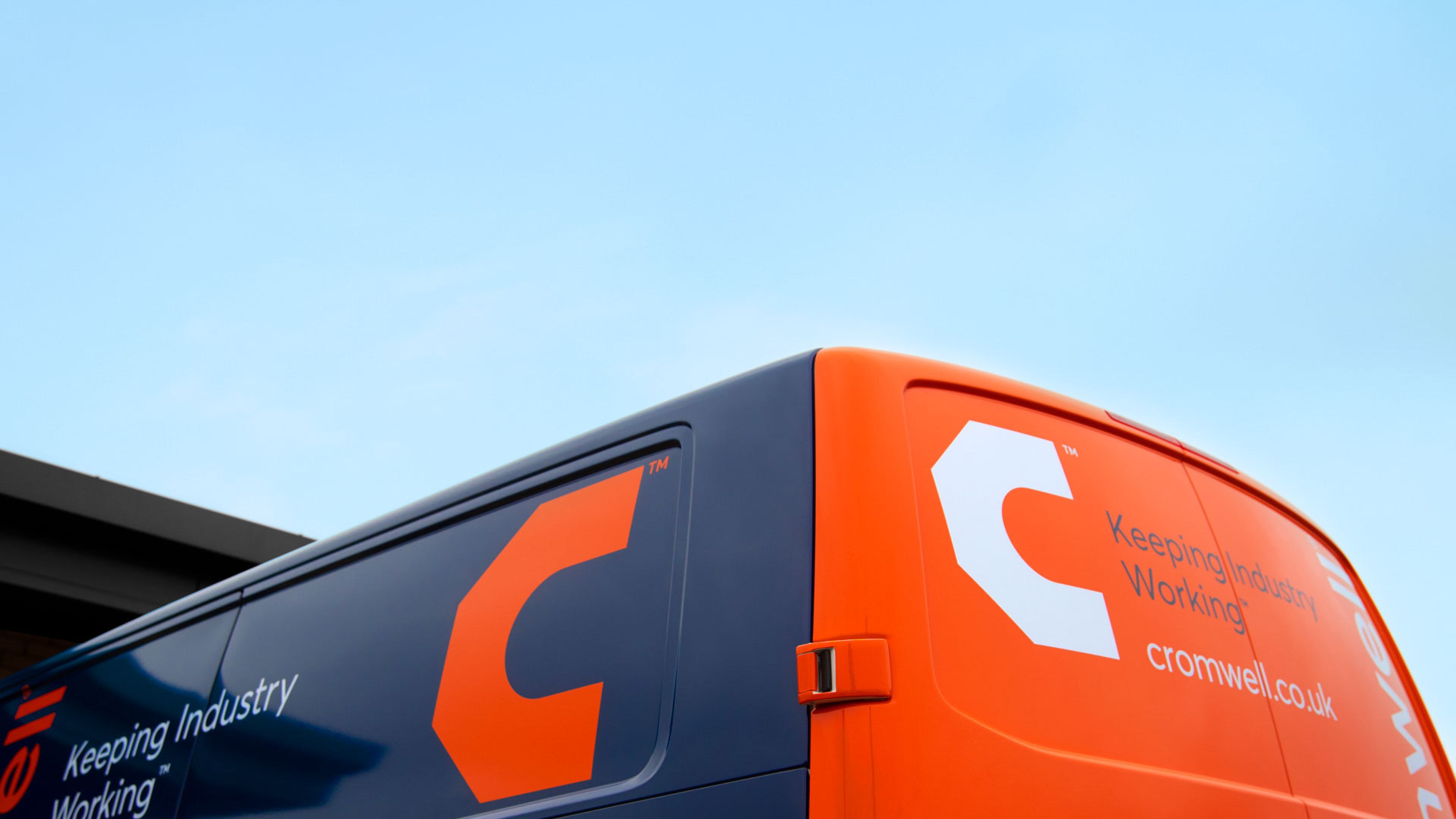 Close up of a corner of a van which is blue and orange, with a large C icon and the words Keeping Industry Working just visible