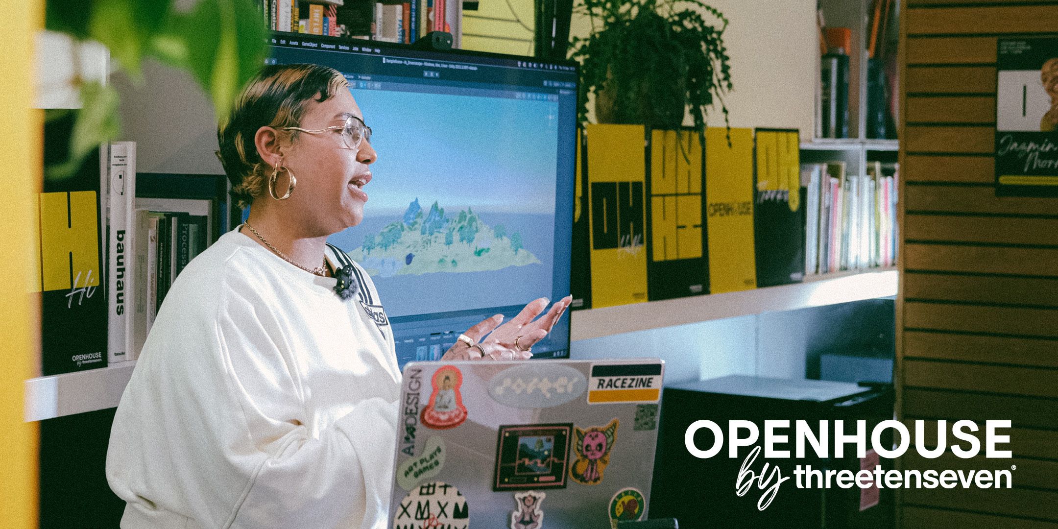 Openhouse by ThreeTenSeven: woman is talking animatedly to an audience, off camera, in a creative studio and with a laptop covered in stickers just in shot.