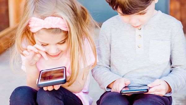 Two children playing with mobile phones