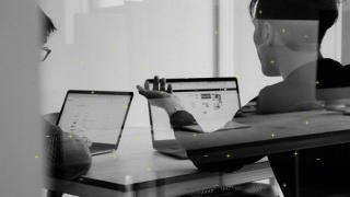 Two people in an office looking at laptops