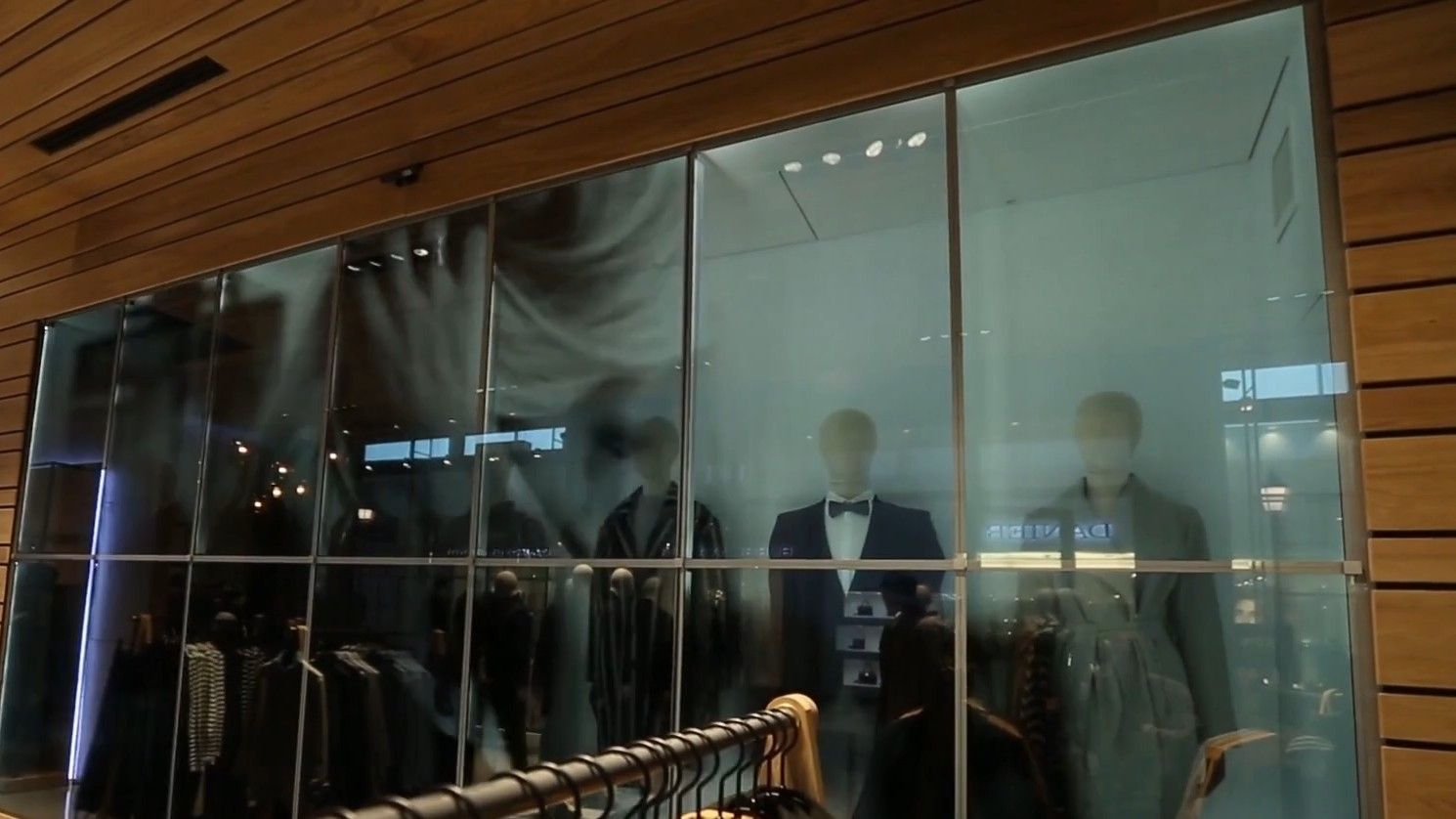 Transparent video wall behind the racks of a fashion store