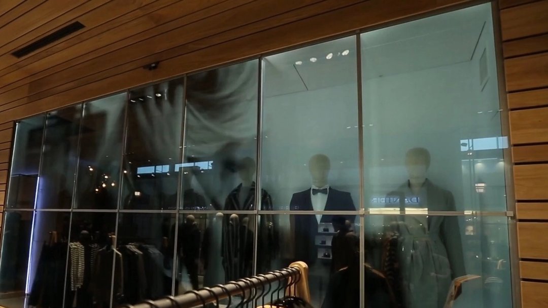 Transparent video wall behind the racks of a fashion store