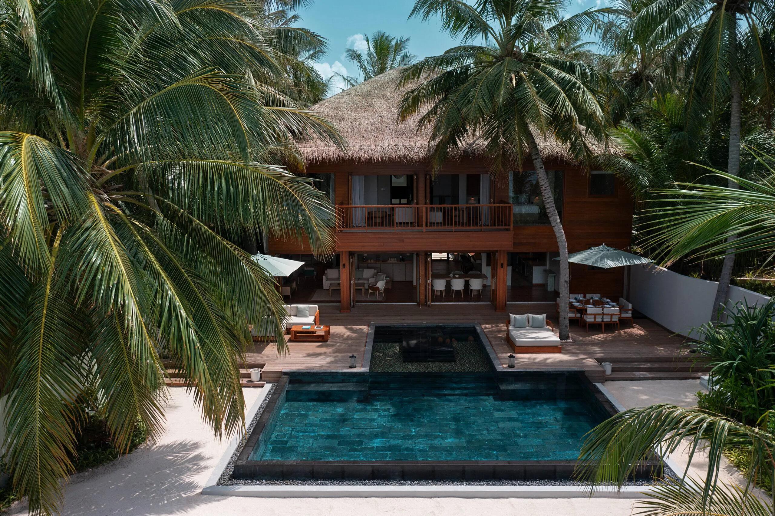 The Two-Bedroom Beach House seen through palm trees, its private pool in the foreground