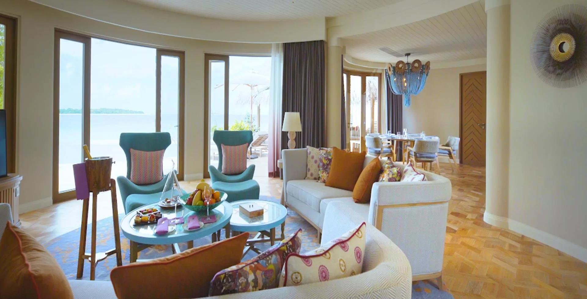 The Nautilus Mansion's living room, teal armchairs facing a dining table and the open ocean beyond.
