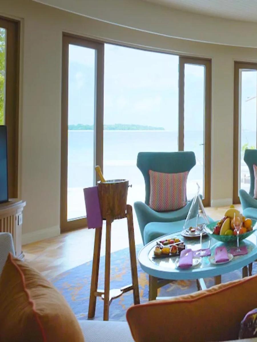The Nautilus Mansion's living room, teal armchairs facing a dining table and the open ocean beyond.